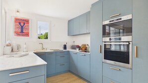 Eine moderne Küche mit hellblauen Schränken, einer weißen Arbeitsplatte und einem eingebauten Backofen.