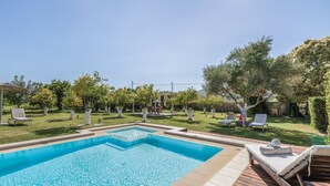 Une piscine rectangulaire dotée d’une terrasse en bois et de chaises longues.