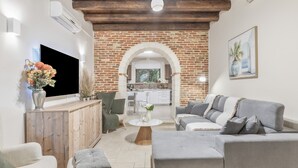 Un salon avec un canapé gris, une table basse en bois et un téléviseur fixé au mur.