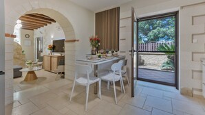 Un espace repas comprenant une table, des chaises et donnant sur l’extérieur.