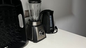 Cozinha com cafeteira, liquidificador e chaleira em uma bancada.