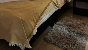 Uma cama com cabeceira, duas mesas de cabeceira, um cobertor e um tapete.