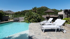 A pool with lounge chairs, a stone pathway, and a mountain backdrop.