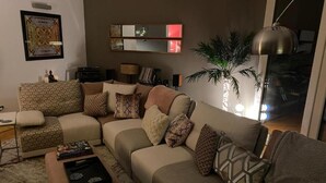 Una sala de estar con un sofá modular, una mesa de centro, una lámpara y un espejo grande en la pared.