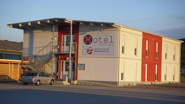 A motel with a signboard, a staircase, and a parked car. - Nibelungenmotel (Poechlarn)