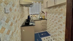 Una cocina compacta equipada con estufa a gas, cafetera y lavabo.