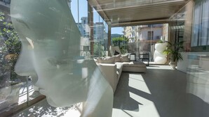 Un intérieur moderne avec un mur de verre, un canapé, un fauteuil et une plante en pot.