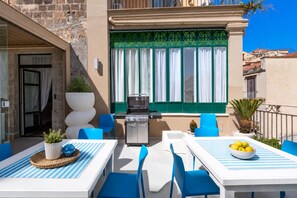 An outdoor patio with a grill, blue chairs, a table with a striped tablecloth, and a bowl of lemons. - AMORE RENTALS - Diamond Home De Luxe - Luxury Apartment with Terrace in Central Sorrento (Sorrento)