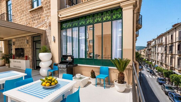 Un espace extérieur aménagé avec un barbecue, des tables, des chaises et des plantes en pot.