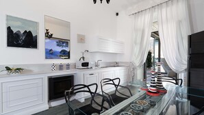 Une cuisine moderne avec des meubles blancs, une table à manger en verre et des objets décoratifs.