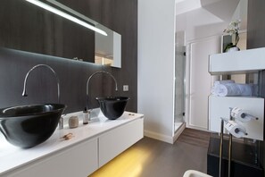 A modern bathroom with two black vessel sinks, a large mirror, and a white vanity with towels. - AMORE RENTALS - Diamond Home De Luxe - Luxury Apartment with Terrace in Central Sorrento (Sorrento)