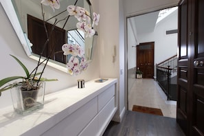 A hallway with a white vanity, a potted orchid, a mirror, and a wooden door. - AMORE RENTALS - Diamond Home De Luxe - Luxury Apartment with Terrace in Central Sorrento (Sorrento)