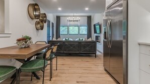 Una cocina moderna con comedor, suelo de madera y un refrigerador de acero inoxidable grande.
