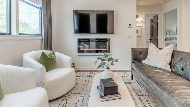 Una sala de estar moderna con televisor de pantalla plana, chimenea, asientos cómodos y vistas al exterior.