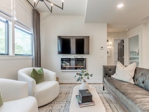 A modern living room with a flat-screen TV, fireplace, comfortable seating, and a view of the outdoors. - Benton LOFT Apartment. Sleeps 4. W-FI. Pets OK! (Edmond)