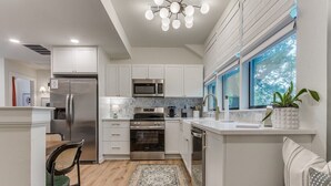 Una cocina moderna con armarios blancos, electrodomésticos de acero inoxidable y suelo de madera.