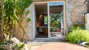 Un edificio rústico con puerta corredera de vidrio que da a un pequeño patio con mesa y sillas.