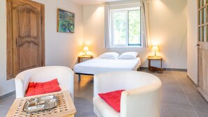 Un dormitorio con una cama, dos mesitas de noche con lámparas, una puerta de madera y un cuadro en la pared.