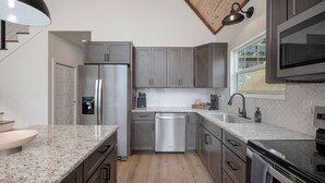 Una cucina moderna con frigorifero in acciaio inox, lavastoviglie e forno, pavimento in legno e una finestra con vista.