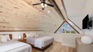 Una camera da letto con due letti, un ventilatore a soffitto, una TV e un'ampia finestra con vista.