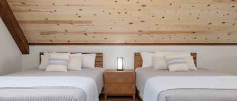 A bedroom with two beds, wooden ceiling, and a nightstand with a mirror.
