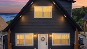 Una casa a due piani con facciata scura, un portone decorato con una ghirlanda e due finestre per piano.