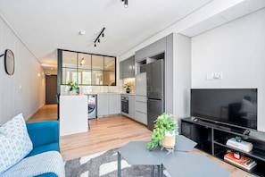 A modern apartment with a kitchen, dining area, living room, and a TV. - The Cedar 202 (Cape Town)