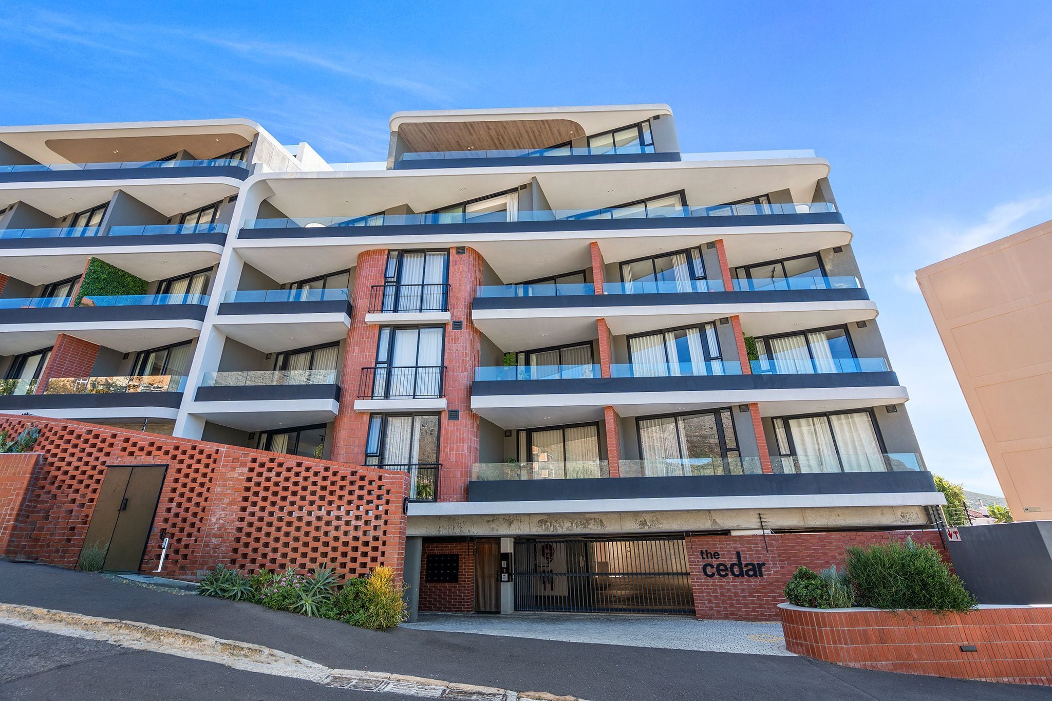 Un hôtel à plusieurs étages, doté de balcons, d’une façade en briques et d’une enseigne indiquant « The Cedar ».