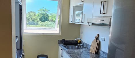 A kitchen with a window, stainless steel appliances, and a tiled floor.
