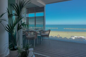 A balcony with a view of the sea, a table with chairs, and potted plants. - Beachfront | Furnished Terrace & Comfort (Civitanova Marche)