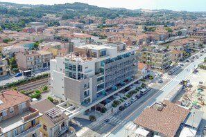 A modern hotel with multiple floors, a central courtyard, and a view of the surrounding urban area. - Beachfront | Furnished Terrace & Comfort (Civitanova Marche)