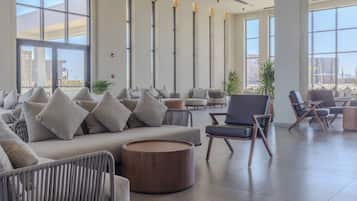 Un vestíbulo amplio con arreglos de asientos, ventanas grandes y vista al exterior.