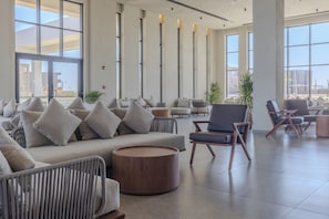 Un vestíbulo amplio con arreglos de asientos, ventanas grandes y vista al exterior.