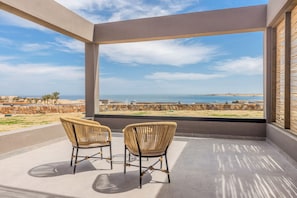 Un balcone con due poltrone in vimini che si affaccia sulla costa.