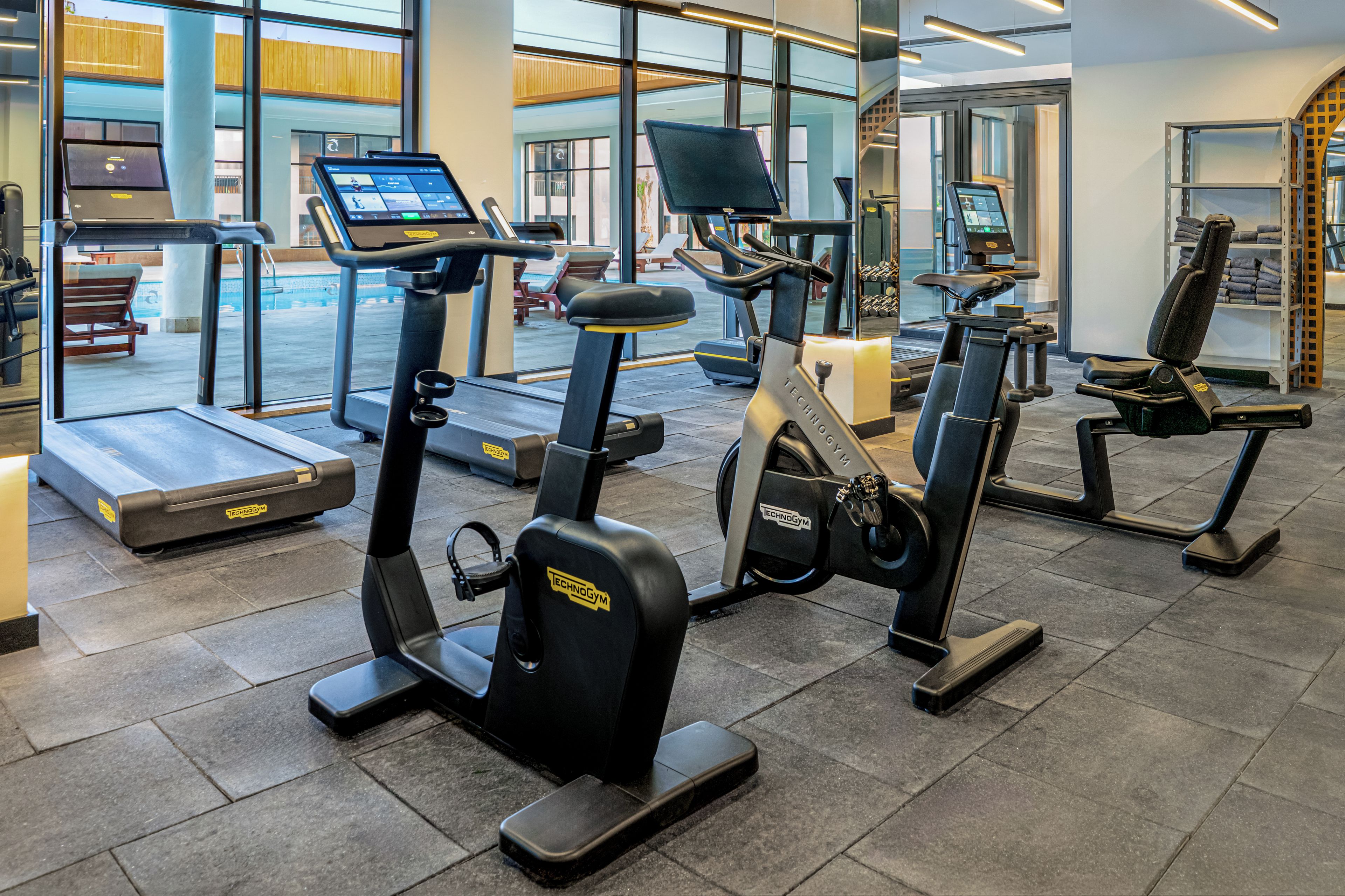 A gym with various exercise equipment including treadmills, stationary bikes, and elliptical machines.