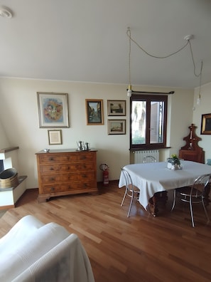 A dining area with a table set for two, a wooden dresser, and framed pictures on the wall.