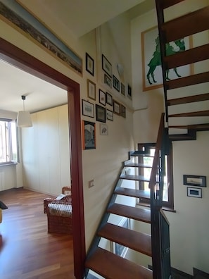 A staircase with a wooden handrail leading to a landing with framed pictures on the wall.