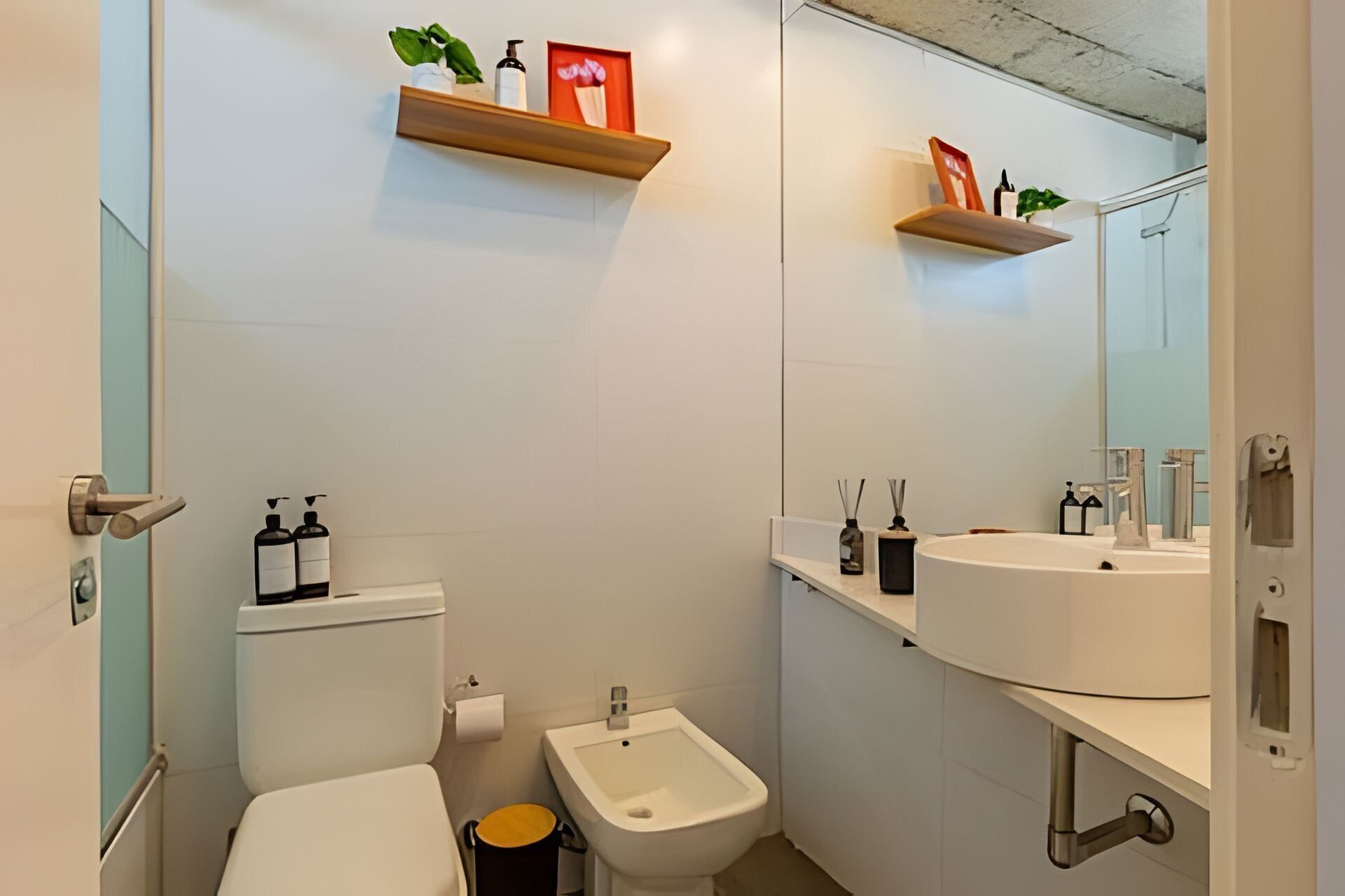 Un baño con inodoro, bidé y lavamanos con espejo.