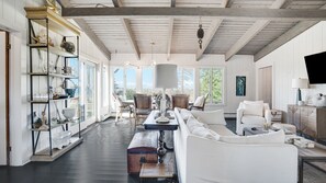 Un vaste salon doté d’un haut plafond, d’étagères intégrées et d’une grande fenêtre offrant une vue sur l’extérieur.