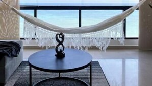A room with a large window, a hammock, a round table, and a couch. - Charming beachfront retreat (Porlamar)