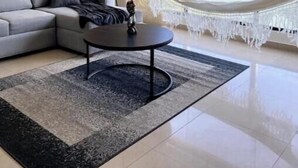 A modern living room with a sofa, a round coffee table, a lamp, a hammock, and a large window with a view. - Charming beachfront retreat (Porlamar)