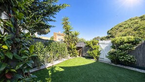 A backyard with a well-maintained lawn, a wooden fence, and various plants. - LVAM - Renovated 2-bedroom apartment – Beach – Garden – Golf 5 (Agde)