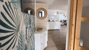 A modern kitchen with white cabinets, a wooden countertop, and a round mirror on the wall. - LVAM - Renovated 2-bedroom apartment – Beach – Garden – Golf 5 (Agde)