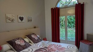 Un dormitorio con cama, lámpara colgante, ventana con cortinas y decoración en la pared.