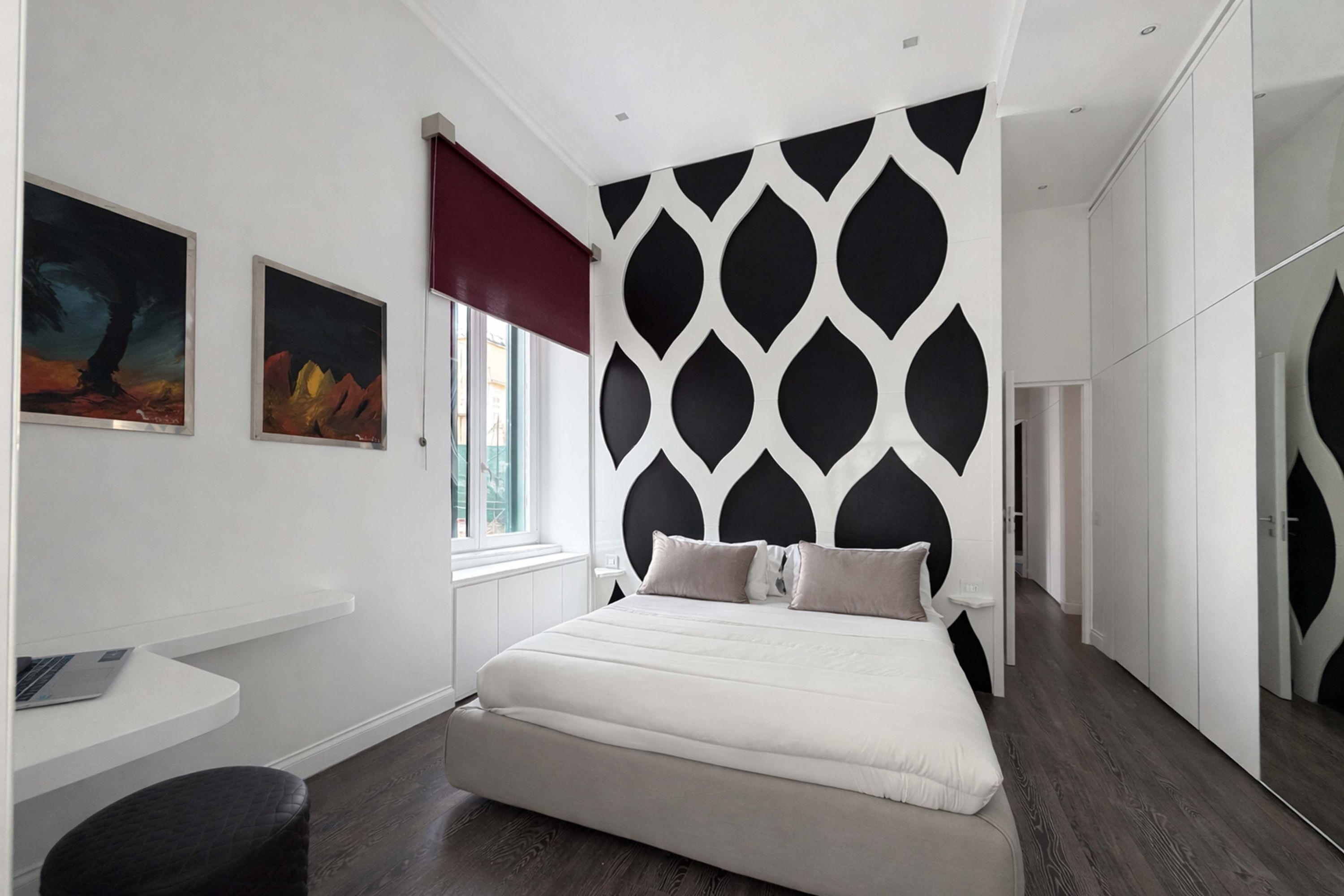 A modern bedroom with a bed, a desk, and artwork on the wall.