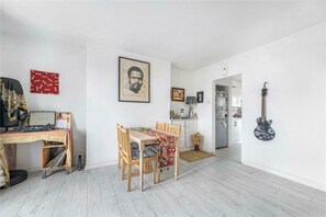 Ein Zimmer mit Esstisch, Stühlen, einer Gitarre und einem gerahmten Bild an der Wand.