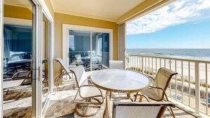 Un balcon avec une porte vitrée, une table ronde et des chaises en osier.