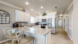 Une cuisine moderne avec des meubles blancs, un îlot en marbre et des appareils électroménagers en acier inoxydable.