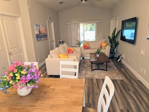 A living room with a sofa, coffee table, and a TV mounted on the wall. - Family Friendly Gem 10 min to Ybor & Downtown! (Tampa)