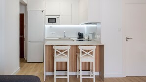 A modern kitchen with a refrigerator, microwave, sink, and two bar stools. - Apartment 'Cozy Sea View Flat' with Sea View, Wi-Fi and Air Conditioning (La Manga)